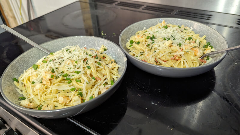 Prawn and chive linguine served in bowls on a stovetop